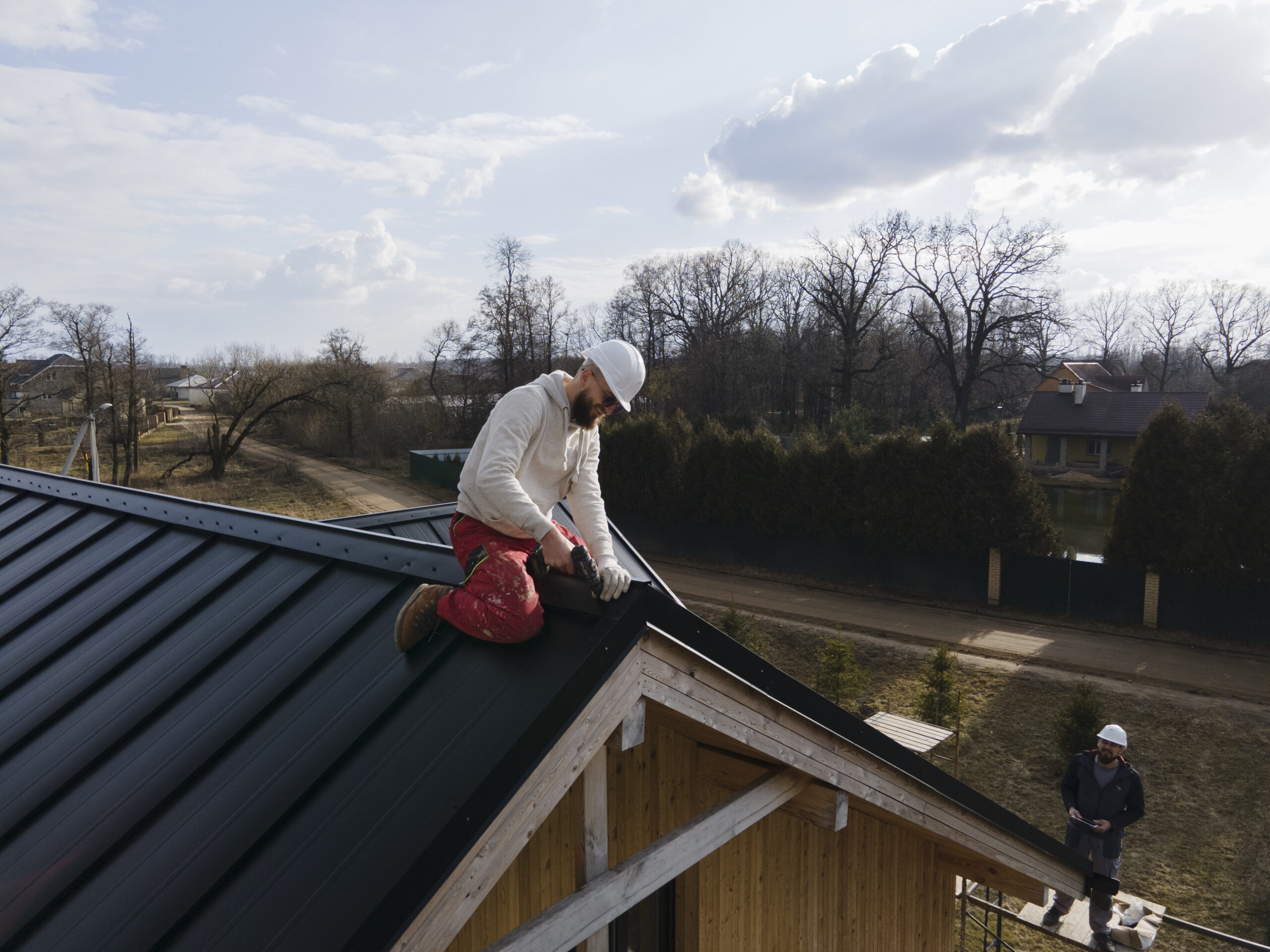 Partially repaired residential roof with visible tools and materials, indicating urgent roofing work in progress.